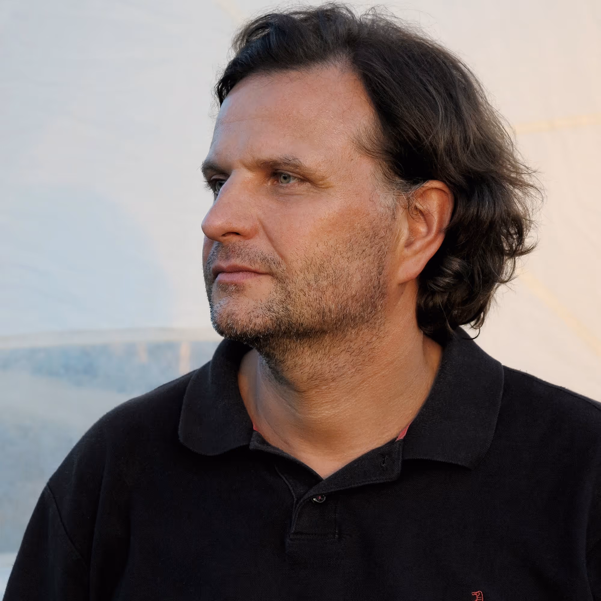 Werner Feiersinger, österreichischer Künstler, 2012 im Porträt, lächelnd im schwarzen Hemd.