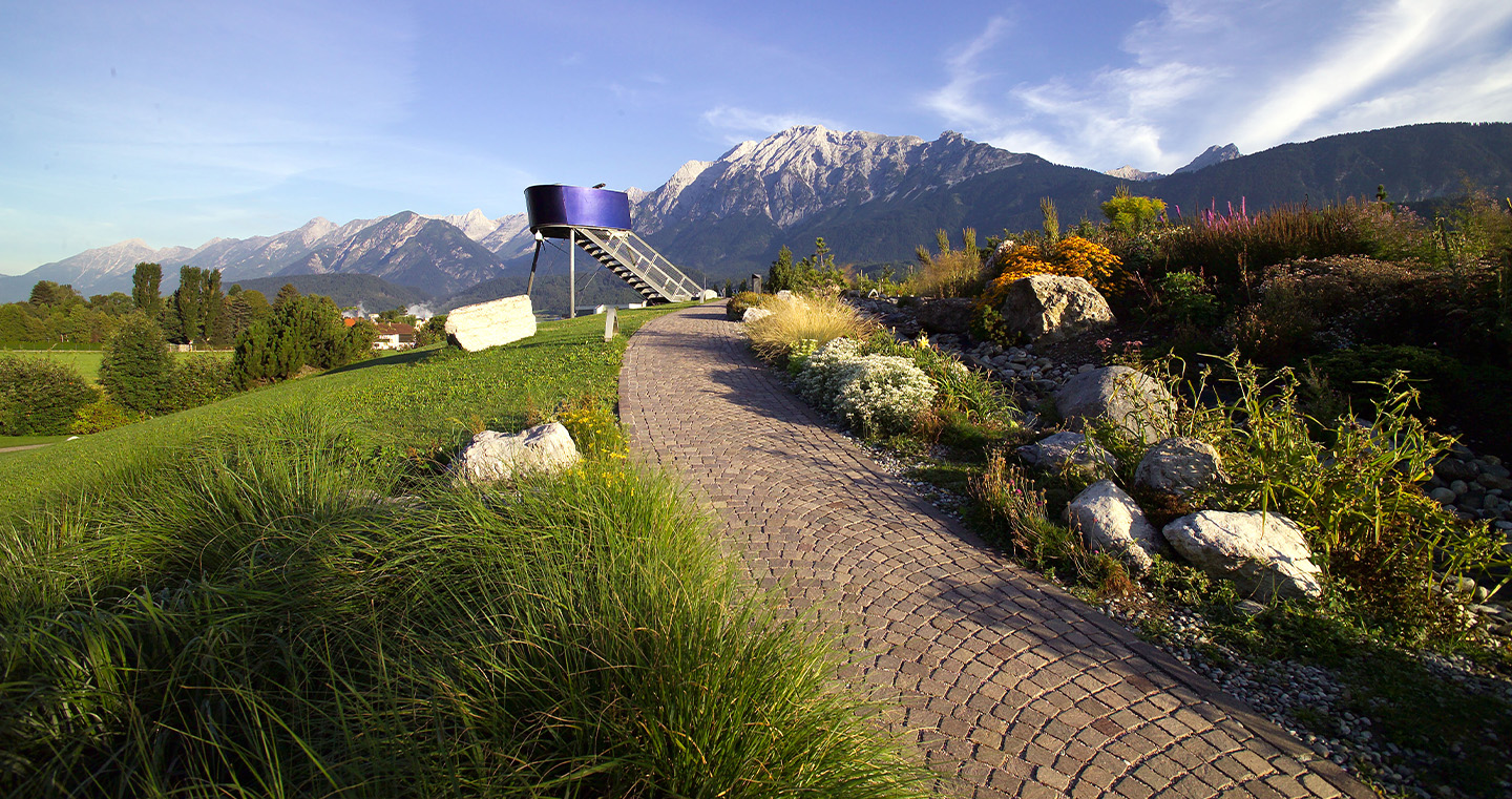 Aussichtsturm im Alpengarten der Swarovski Kristallwelten: Moderner Metallturm mit Blick auf die Tiroler Bergwelt.