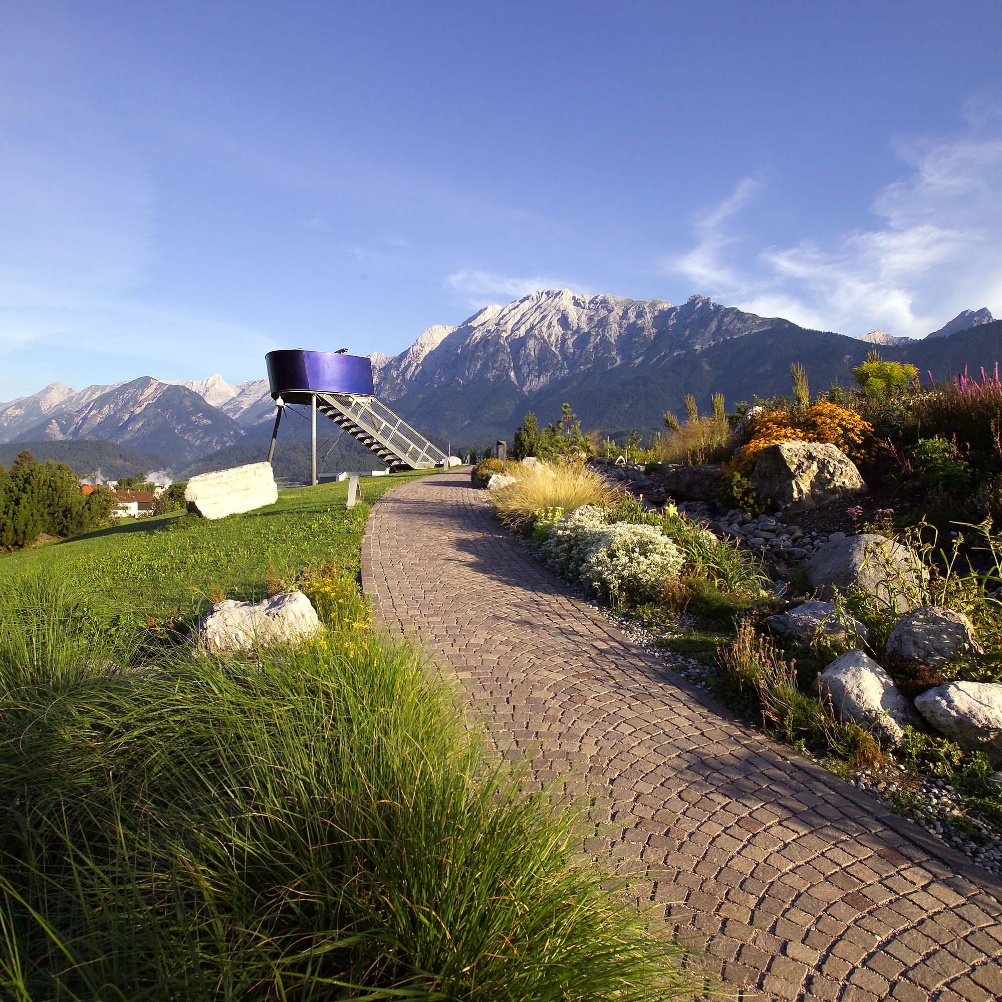 Aussichtsturm im Alpengarten der Swarovski Kristallwelten: Moderner Metallturm mit Blick auf die Tiroler Bergwelt.