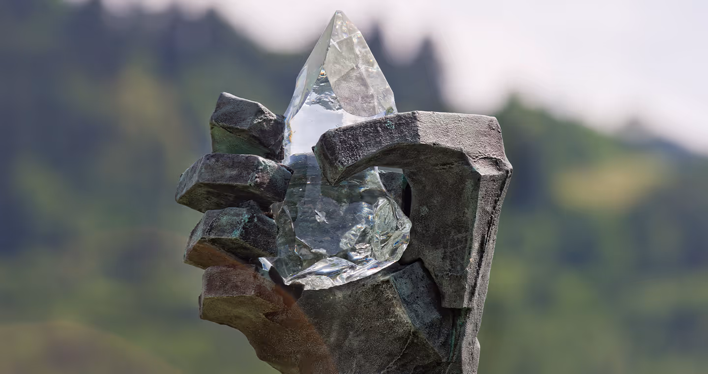 Skulptur 'Airs and Graces': Monumentale Bronzeskulptur einer Hand, die einen Kristall hält, im Park aufgestellt.