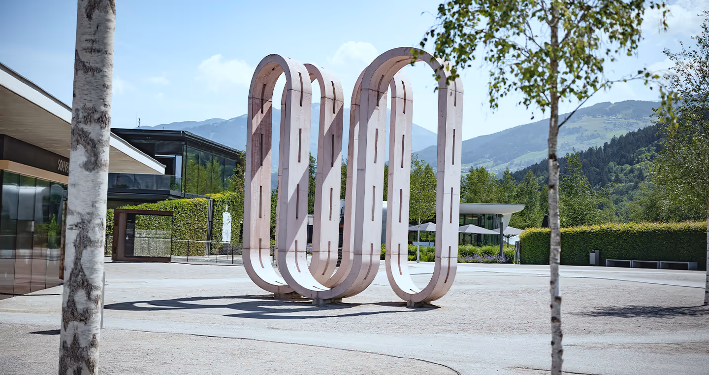 Kunstwerk 'Conveyor Belt': Große rosafarbene Skulptur im Freien, bestehend aus geschwungenen, organischen Formen.