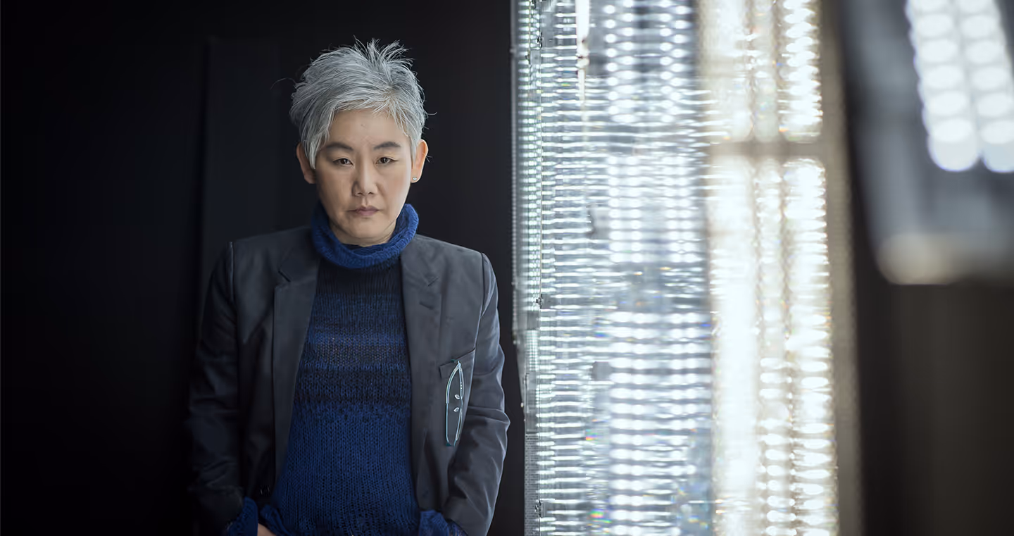 Lee Bul, südkoreanische Künstlerin, 2015 im Porträt mit grauen Haaren und blauer Kleidung, ernst in die Kamera blickend.