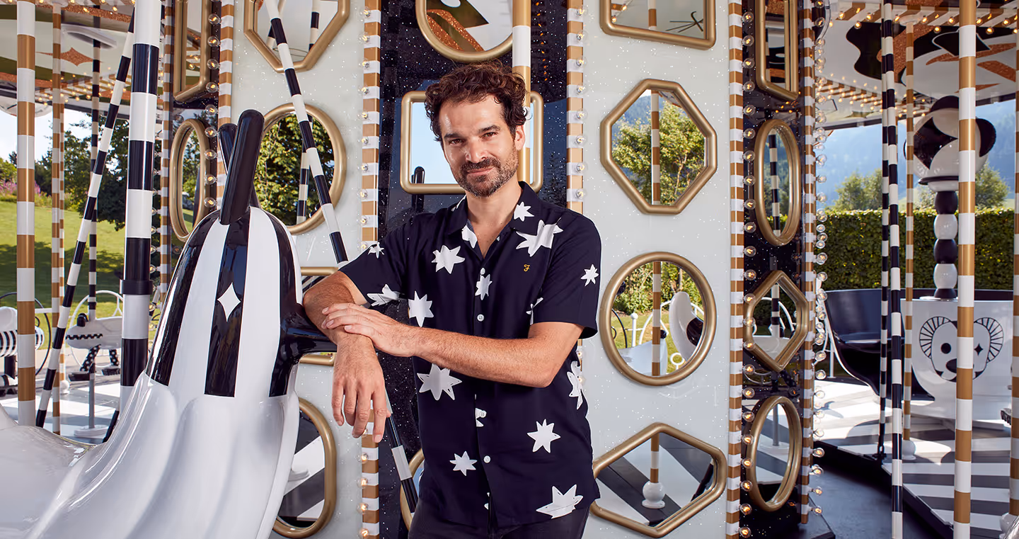 Jaime Hayon, spanischer Designer, 2019 in auffälliger Sternenbluse, lachend vor seiner Karussell-Installation.