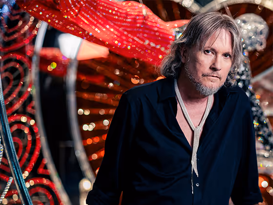 Michael Schmidt, amerikanischer Designer, 2023 im schwarzen Hemd, stehend vor seiner Bühneninstallation in den Swarovski Kristallwelten.