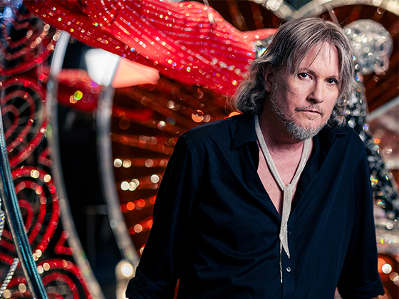 Michael Schmidt, amerikanischer Designer, 2023 im schwarzen Hemd, stehend vor seiner Bühneninstallation in den Swarovski Kristallwelten.