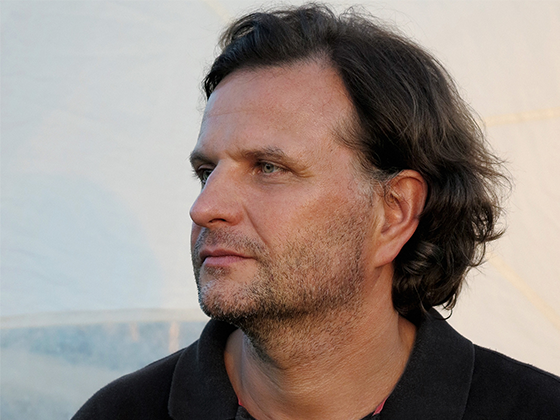 Werner Feiersinger, österreichischer Künstler, 2012 im Porträt, lächelnd im schwarzen Hemd.