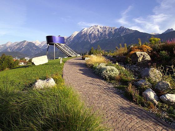 Aussichtsturm im Alpengarten der Swarovski Kristallwelten: Moderner Metallturm mit Blick auf die Tiroler Bergwelt.