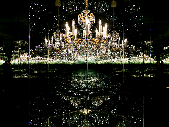Kunstwerk 'Chandelier of Grief': Ein Kristallluster in einem Spiegelraum, der durch Reflexionen endlos erscheint.