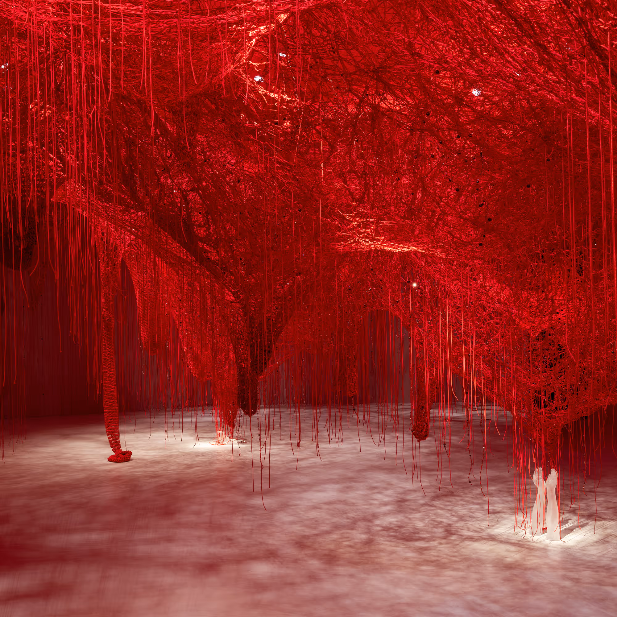 Rauminstallation 'Crystallizing Identity': Hunderte rote Fäden spannen sich durch den Raum und erzeugen ein dichtes Netz aus Licht und Schatten.