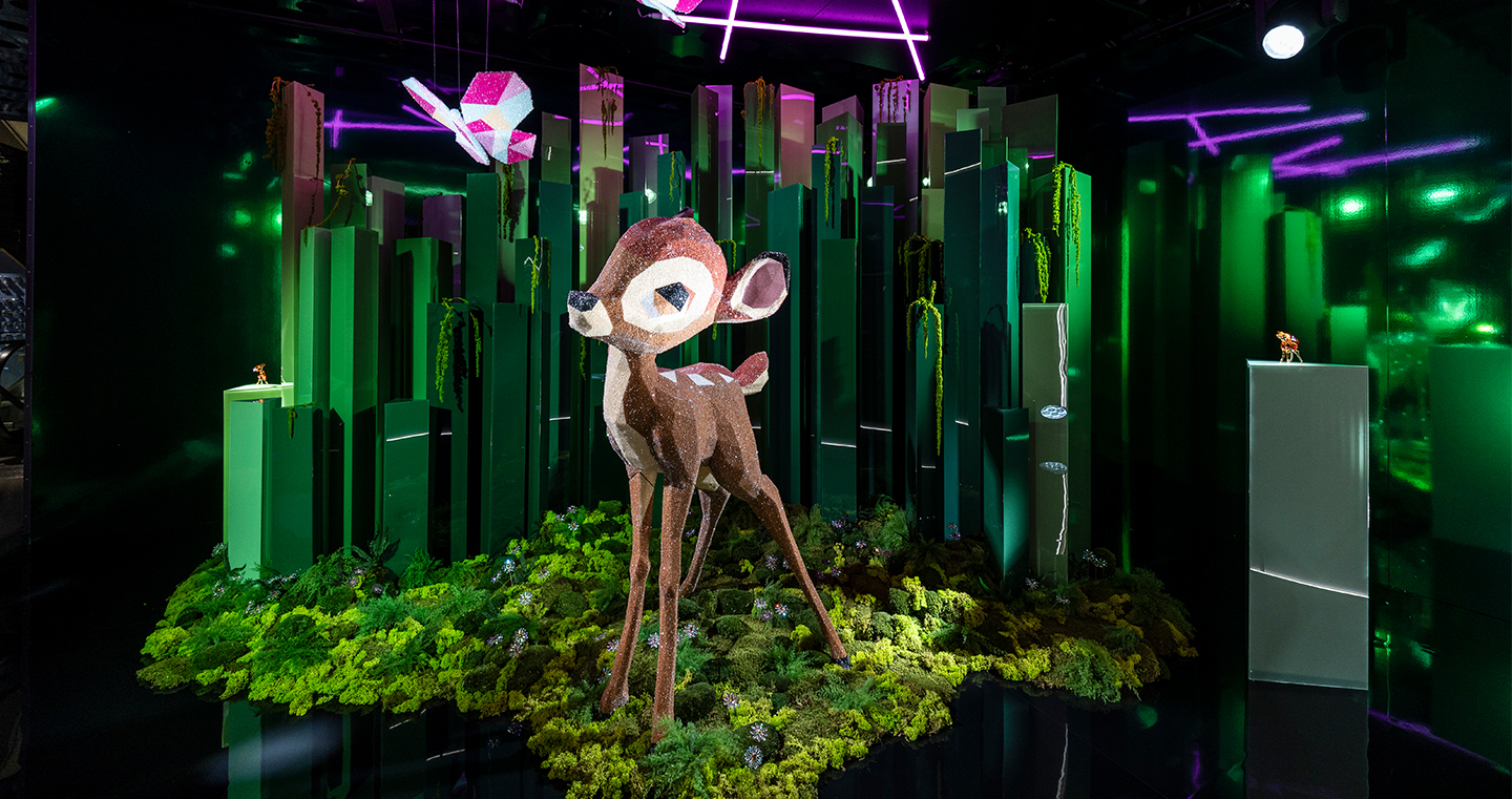 Kristallisiertes Bambi in einem Schaufenster, im Hintergrund grüne Stelen welche einen Wald darstellen sollen.