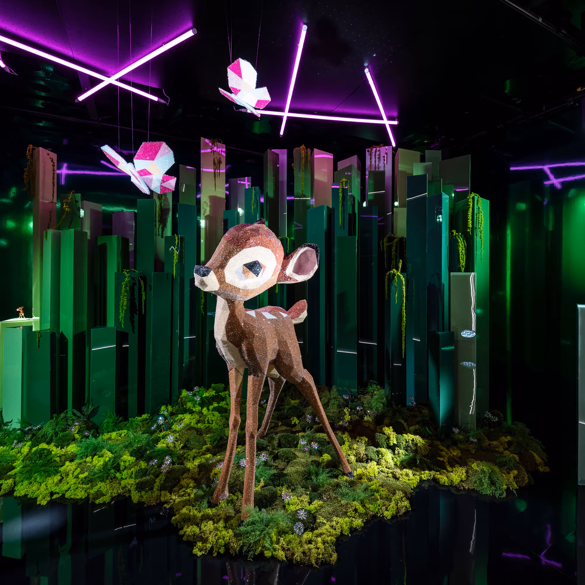 Kristallisiertes Bambi in einem Schaufenster, im Hintergrund grüne Stelen welche einen Wald darstellen sollen.