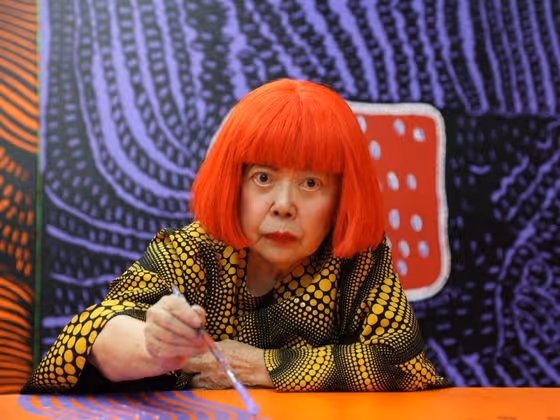 Yayoi Kusama, japanische Künstlerin, im Porträt mit rotem Haarschnitt, bekannt für ihre Polka-Dot-Muster.