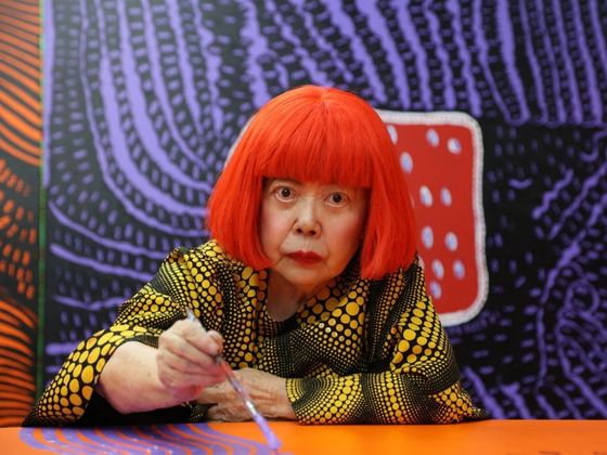Yayoi Kusama, japanische Künstlerin, im Porträt mit rotem Haarschnitt, bekannt für ihre Polka-Dot-Muster.