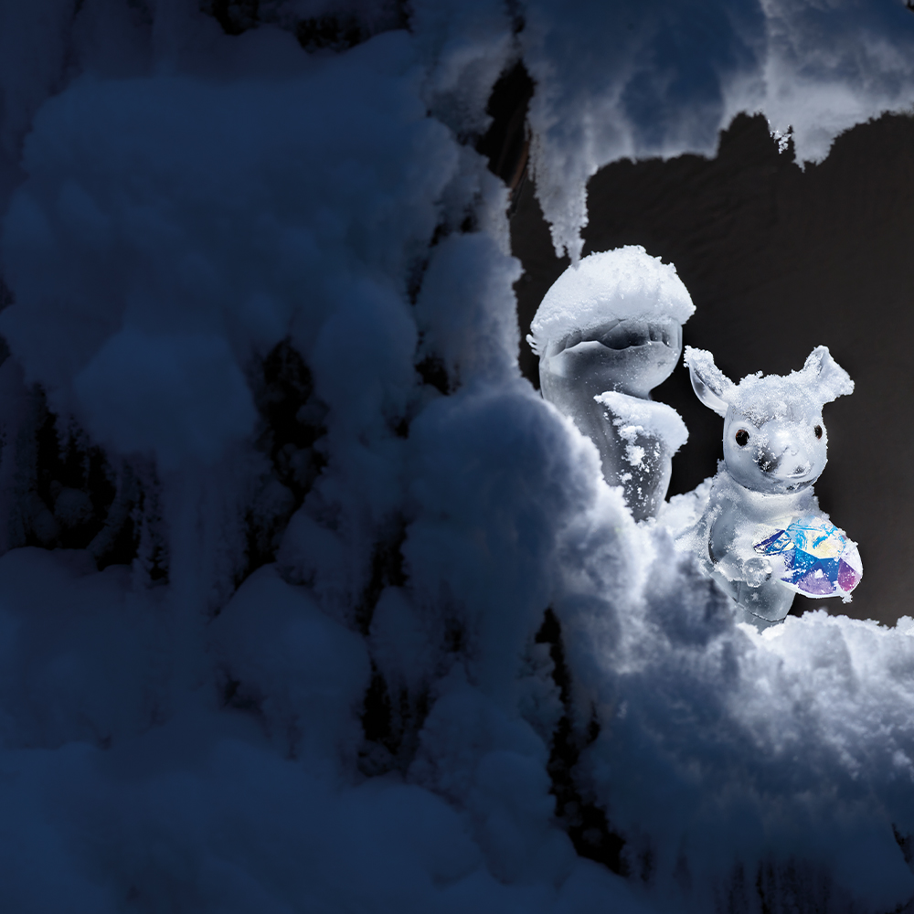Verschneites Eichhörnchen sitzt in einer schneebedeckten Baumhöhle der Wunderkammer Silent Light in den Swarovski Kristallwelten.