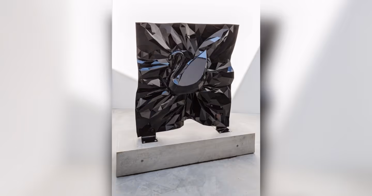 Large-scale black sculpture with a crystal-like surface and swan motif in a minimalist exhibition space.