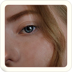 Close-up of a woman's eye with light brown hair partially covering her face.