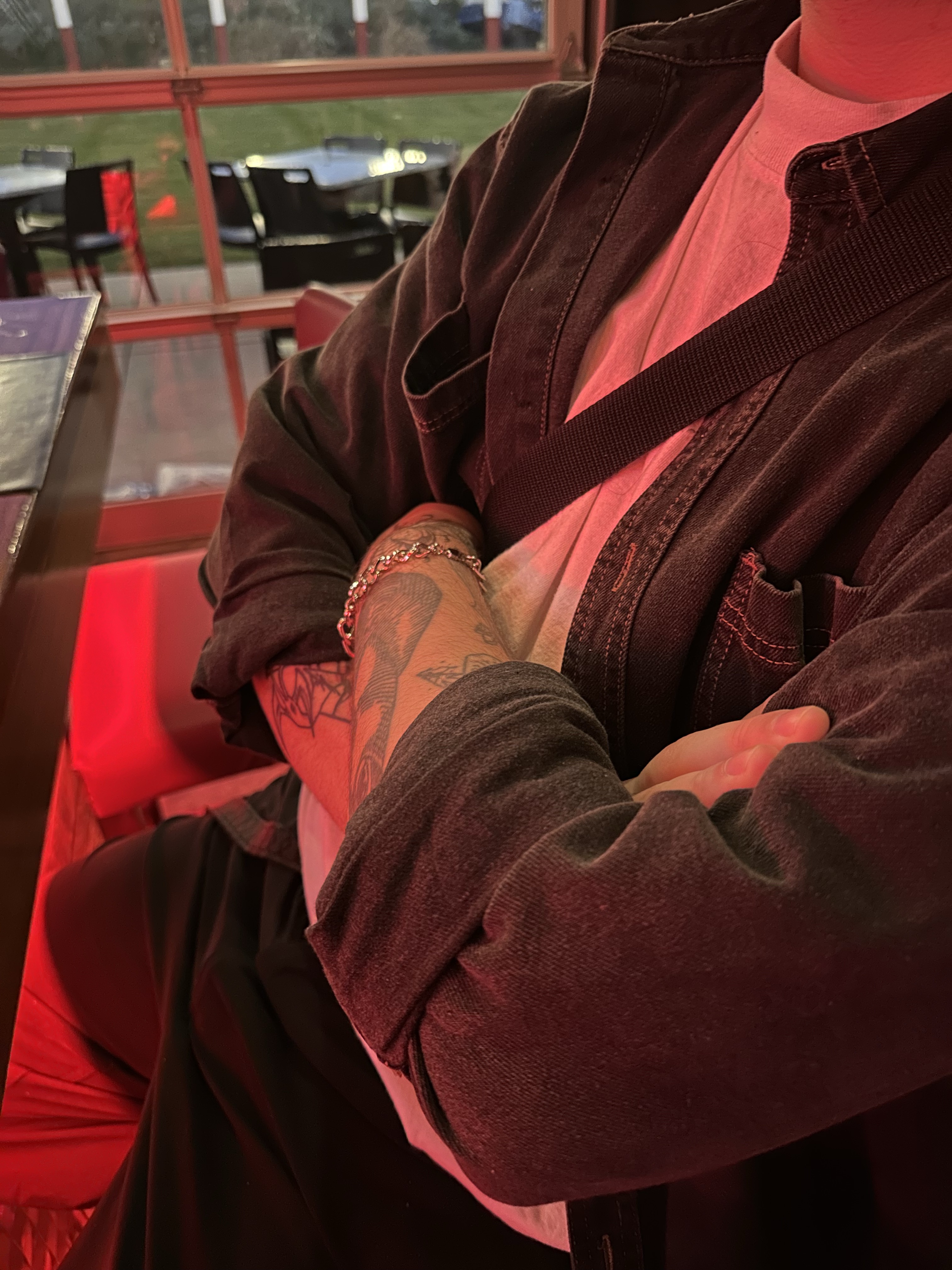 A man sitting on a couch, wrapping his hands aroung his head.