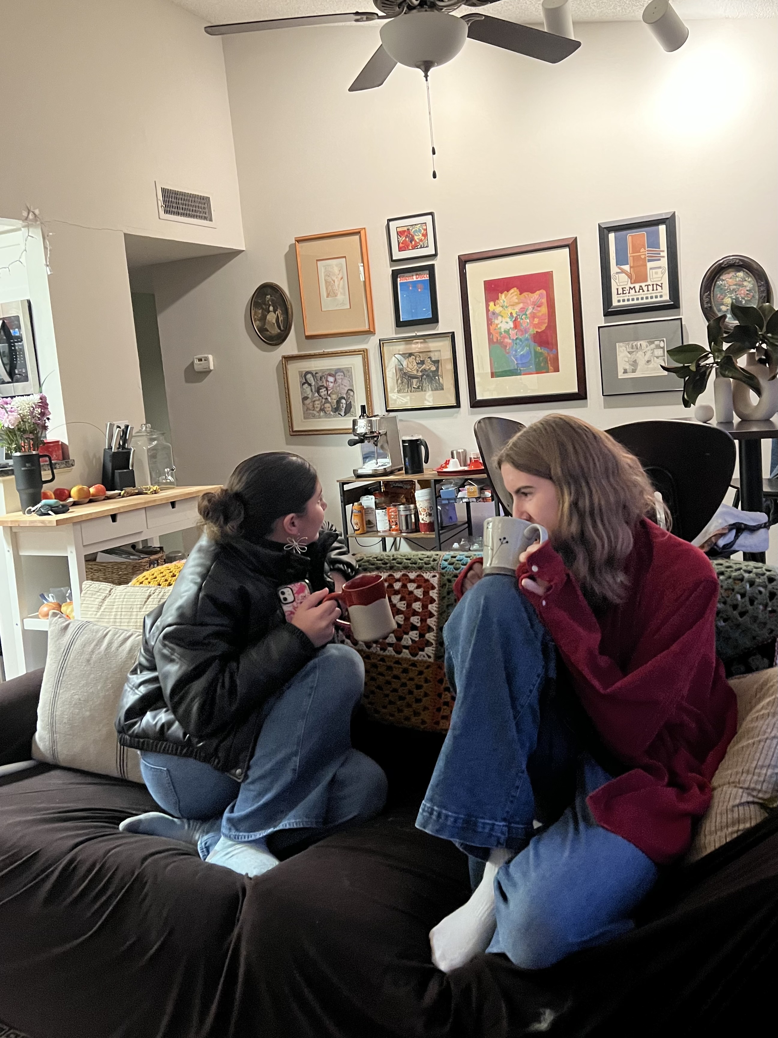 Zwei Personen sitzen entspannt im WG-Wohnzimmer und unterhalten sich. Ein Symbolbild für Freunde finden im Alltag.