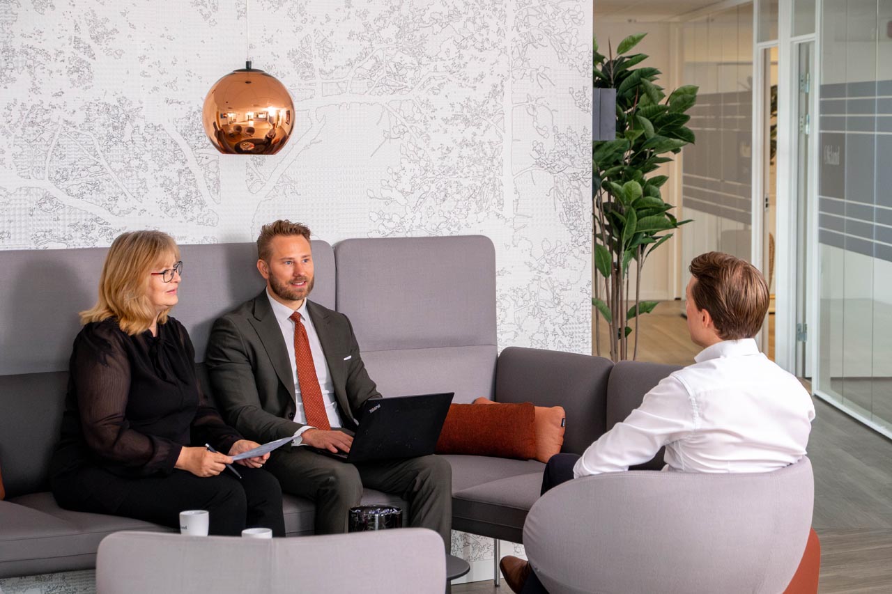 3 ansatte i advokatfirmaet økland som snakker sammen i en sofa