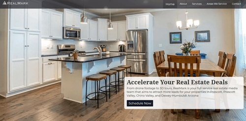 Modern kitchen with white cabinets, stainless steel appliances, an island with bar stools, and a wooden dining table with chairs and a floral centerpiece.