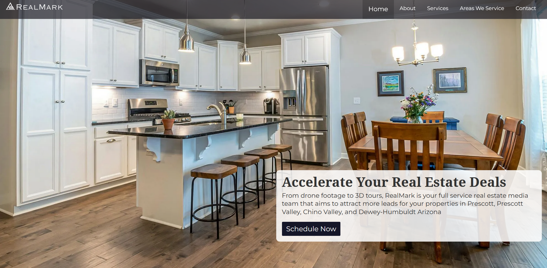 Modern kitchen with white cabinets, stainless steel appliances, an island with bar stools, and a wooden dining table with chairs and a floral centerpiece.