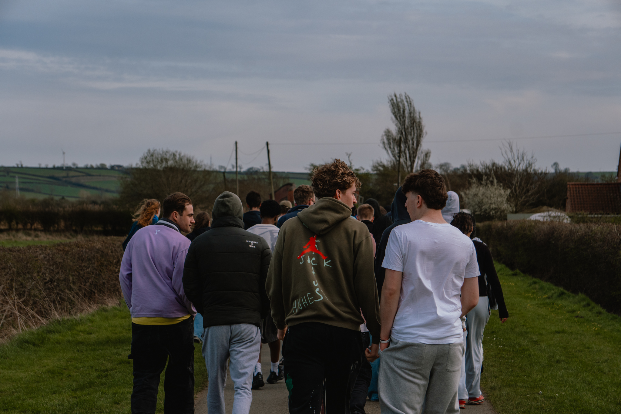 A group of students walking through the countryside chatting with each other.