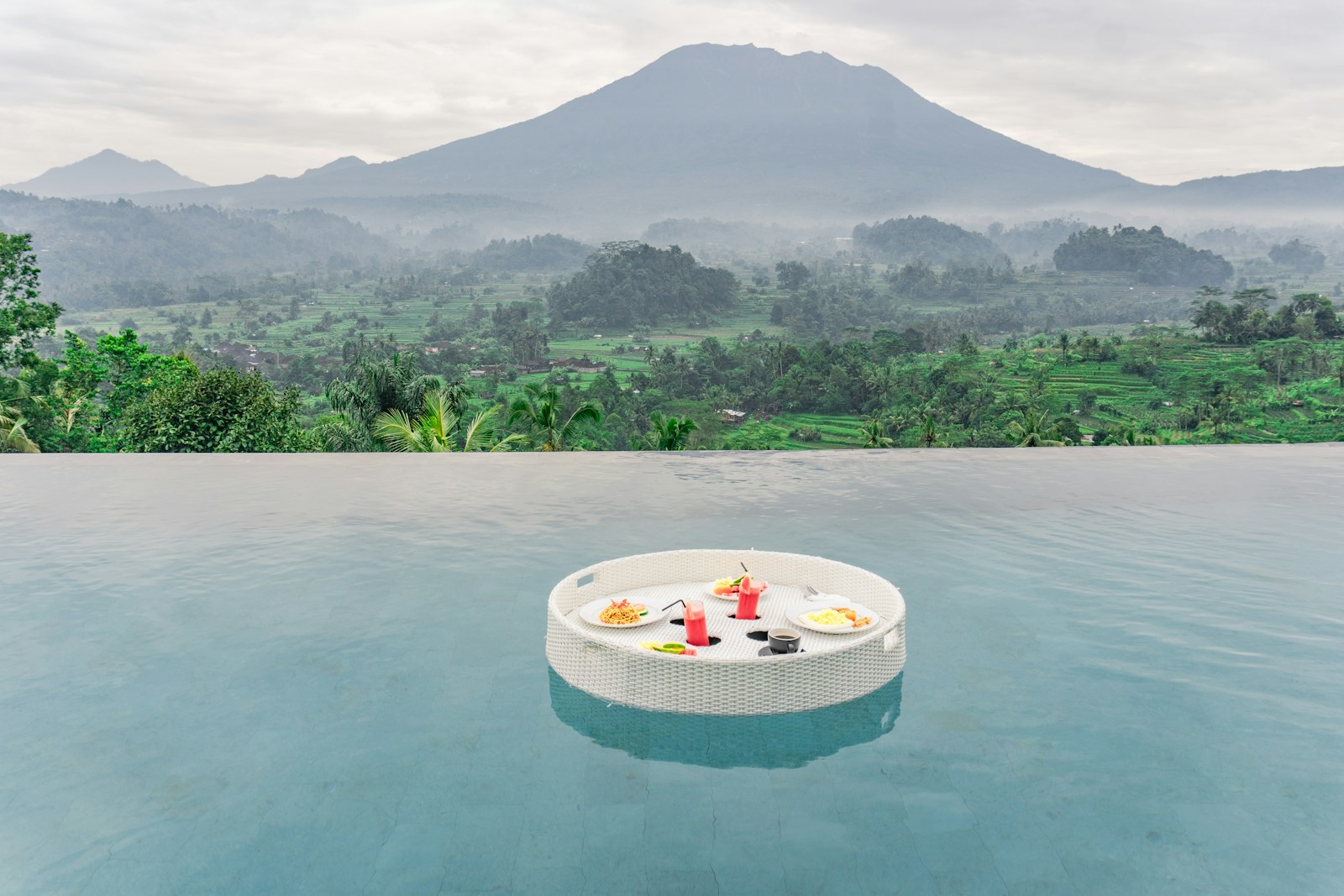 Floating breakfast tray in a pool overlooking a volcanic landscape