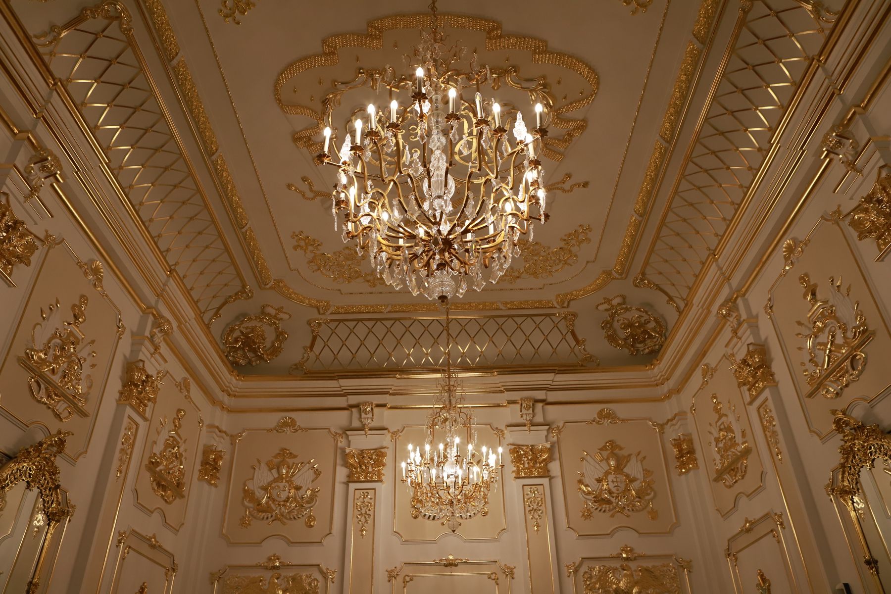 Golden chandelier beneath an ornate palace ceiling