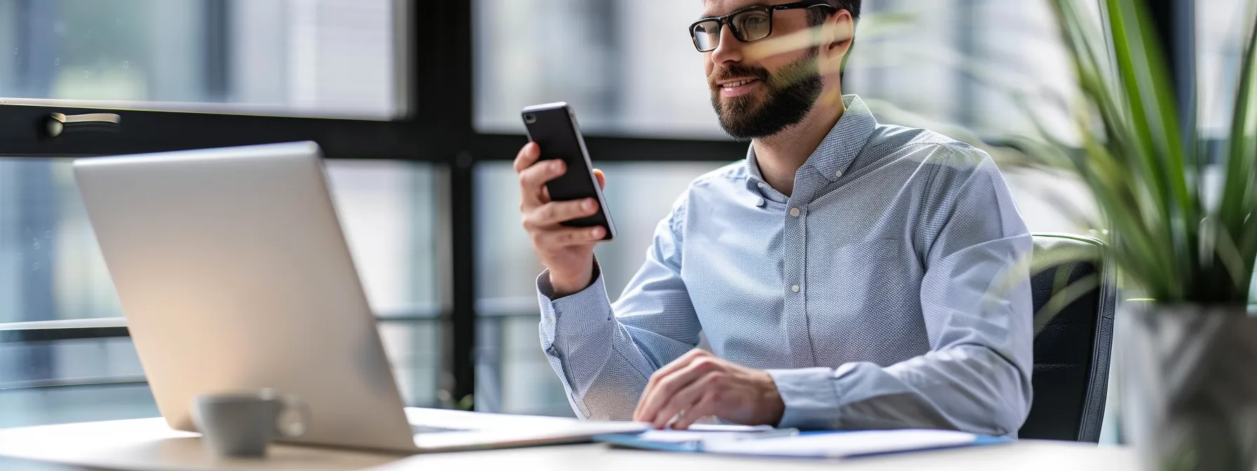 a person sitting at a desk with a laptop, phone in hand, ready to provide technical support.