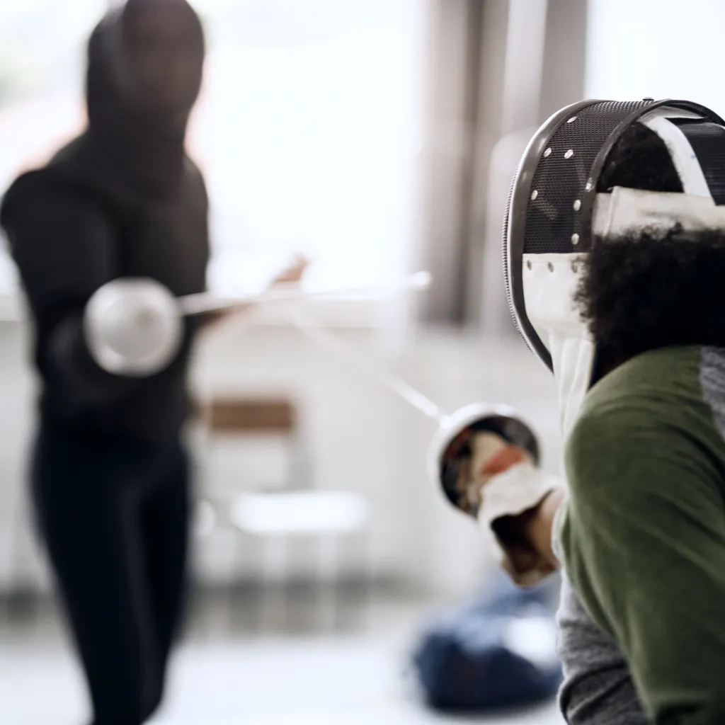 Teen fencer receiving a one-on-one epee lesson in a bright Watertown, MA fencing studio, focused on developing technique and confidence.