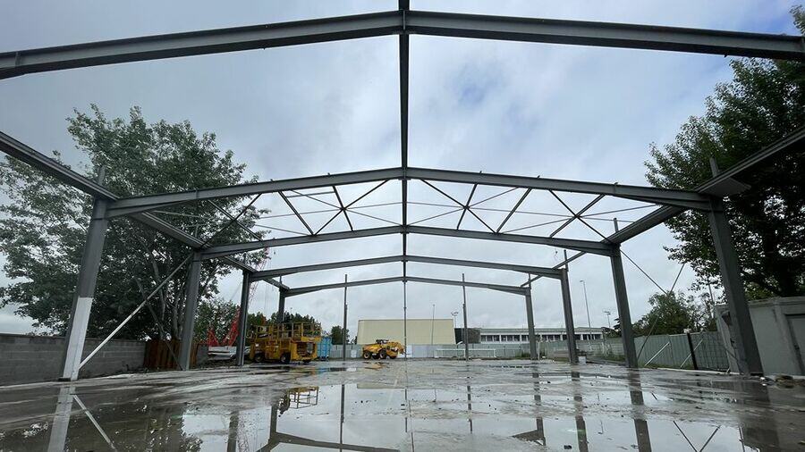 Charpente métallique en cours de montage sur un chantier, sous un ciel nuageux