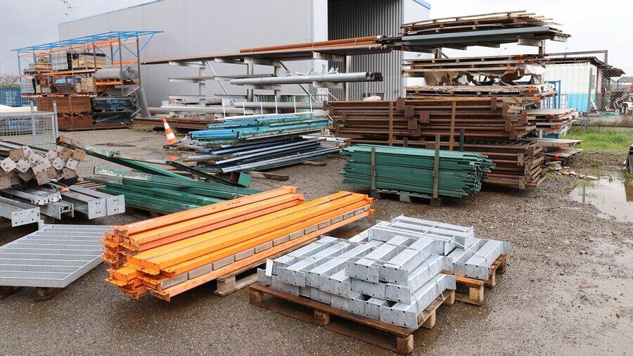 Stock de poutres et éléments métalliques triés sur palettes dans une cour industrielle.