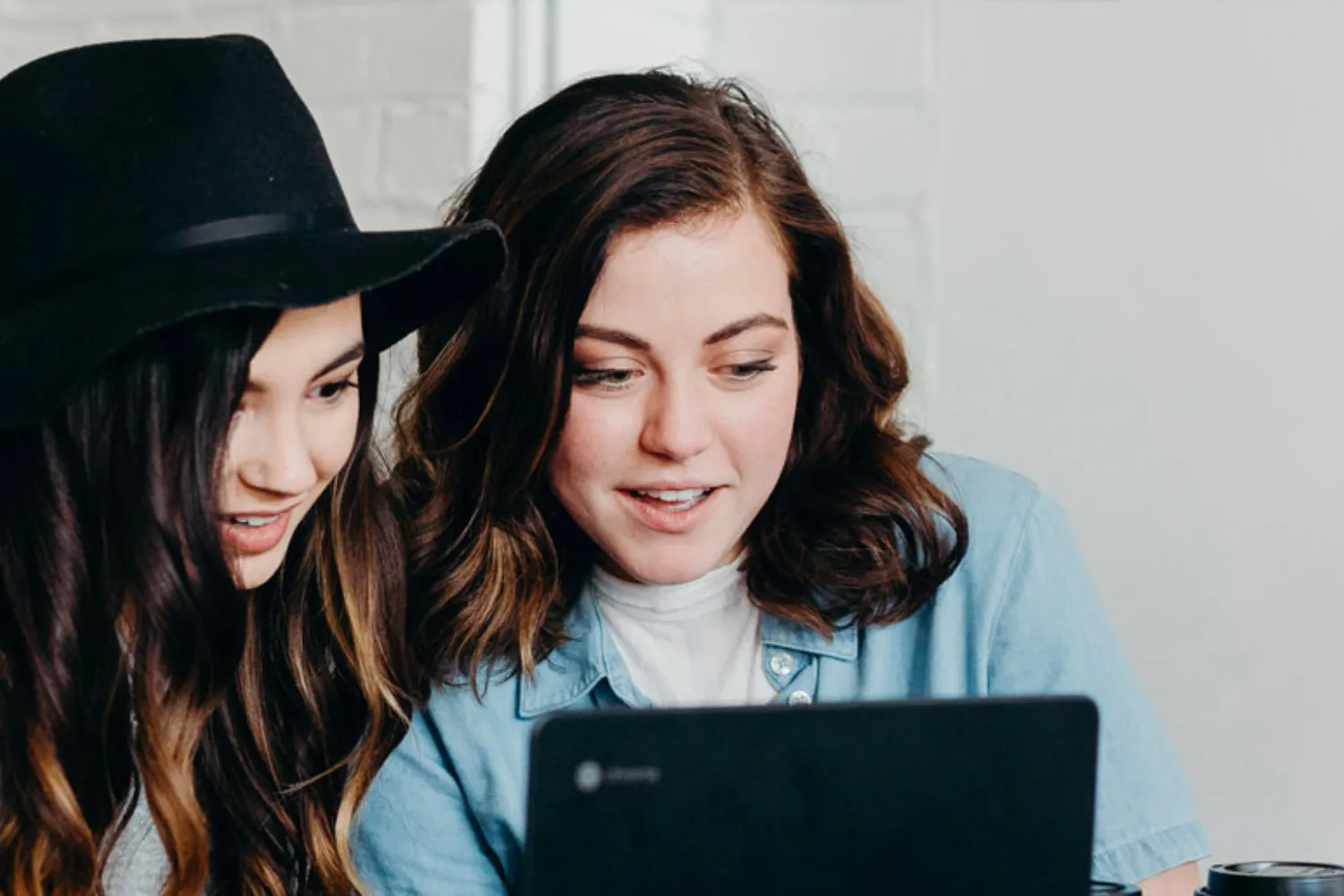 Deux jeunes femmes regardent ensemble l’écran d’un ordinateur portable