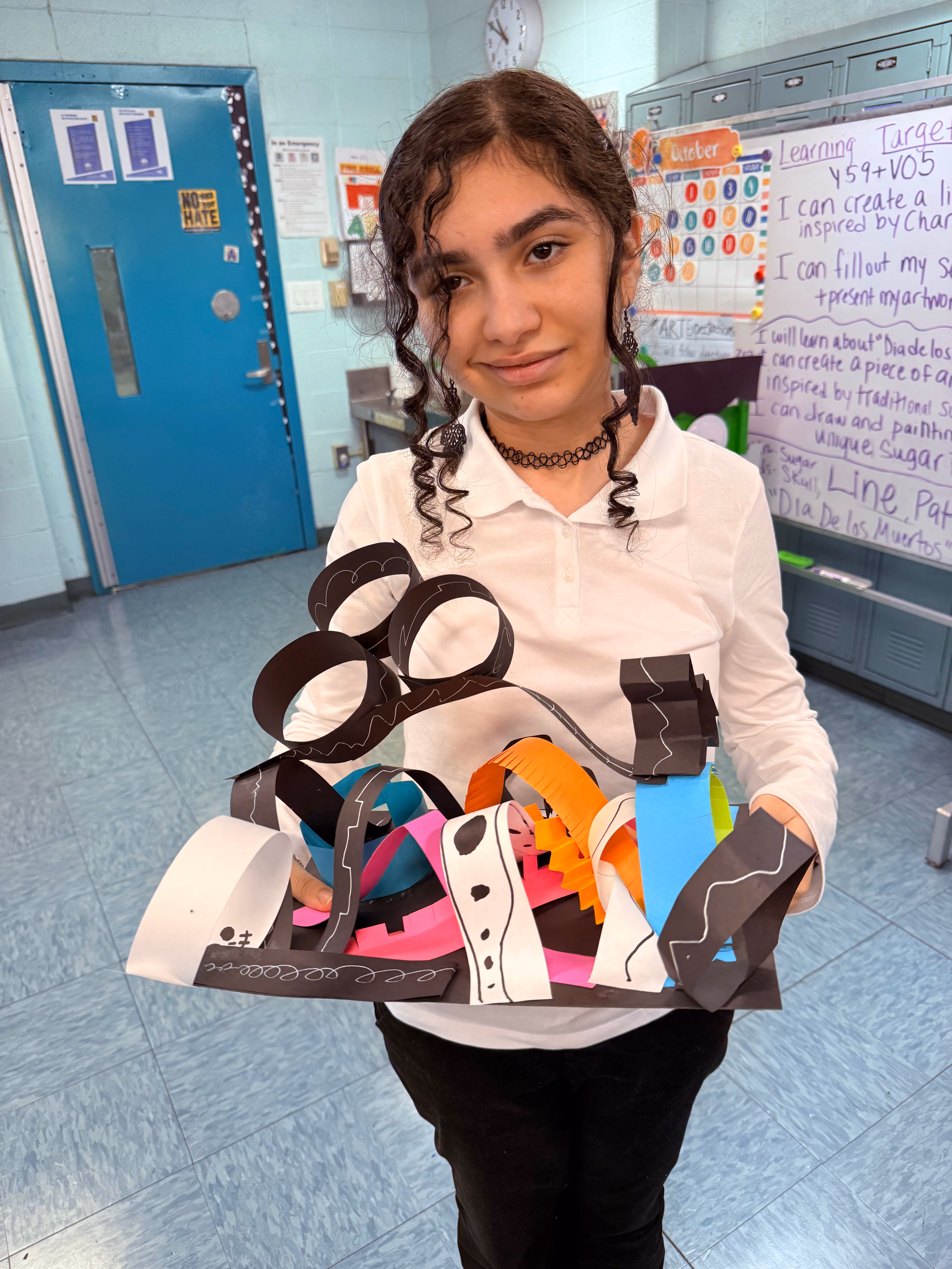 Student holding colorful paper sculpture inspired by Día de los Muertos