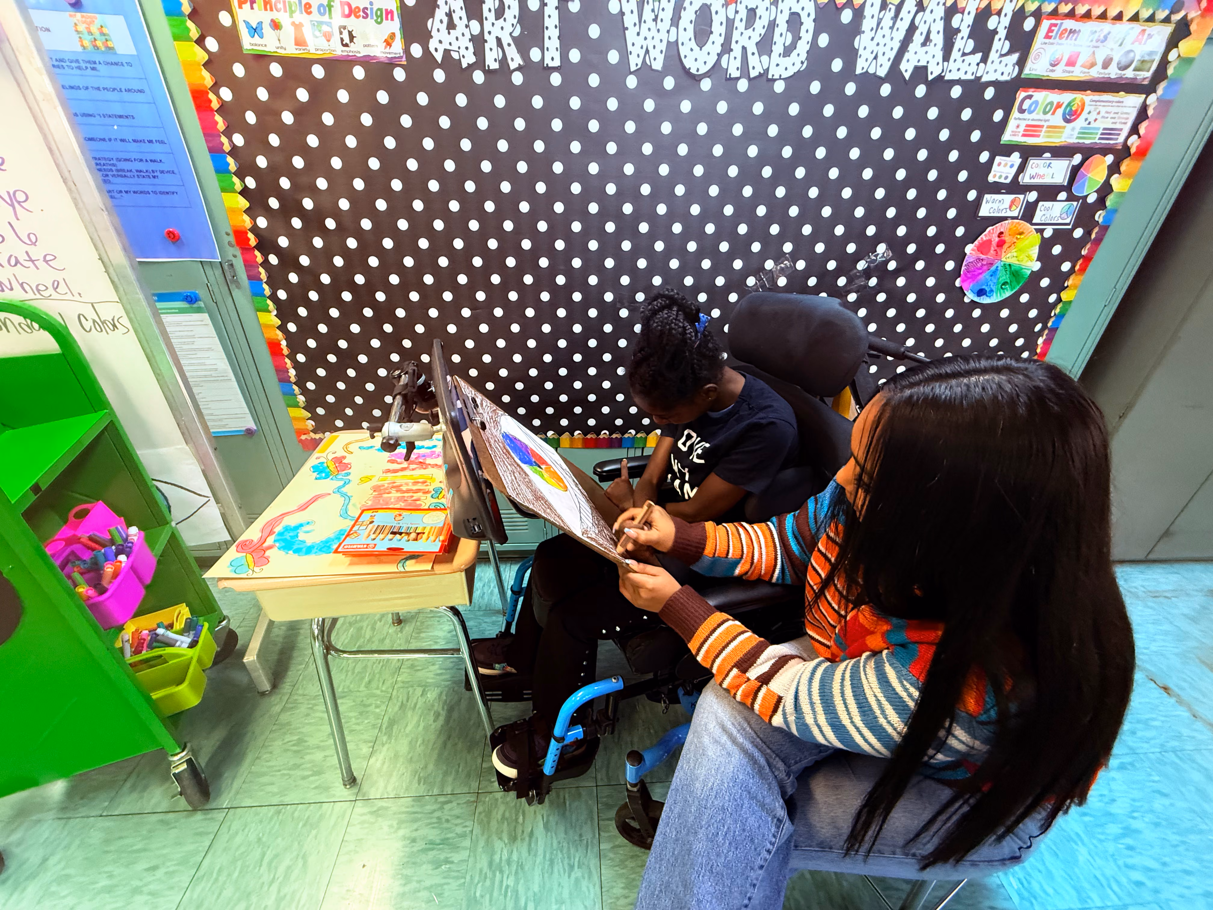 Two students drawing colorful artwork in an elementary art classroom