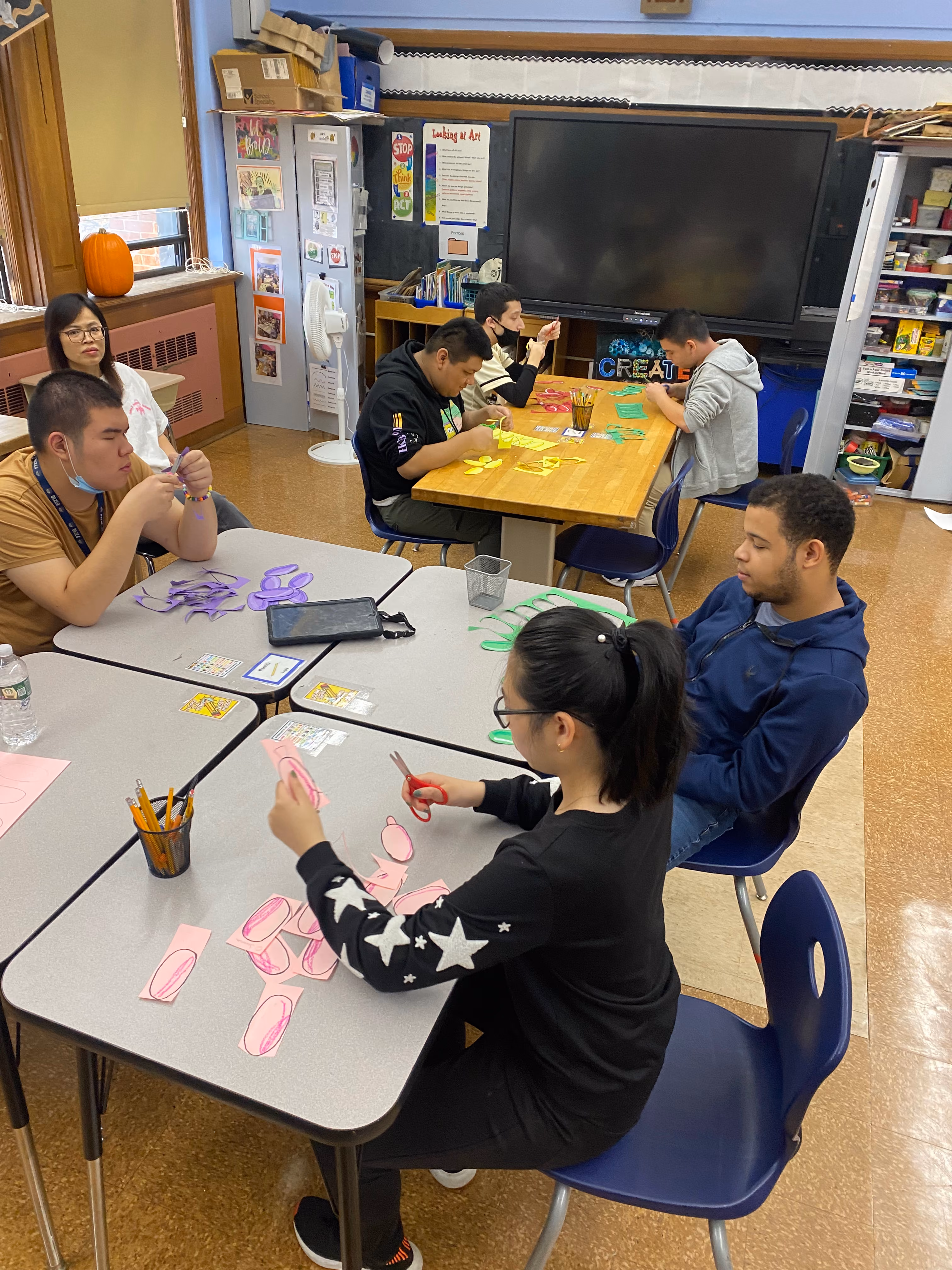 Students cutting and assembling colorful paper shapes in art class
