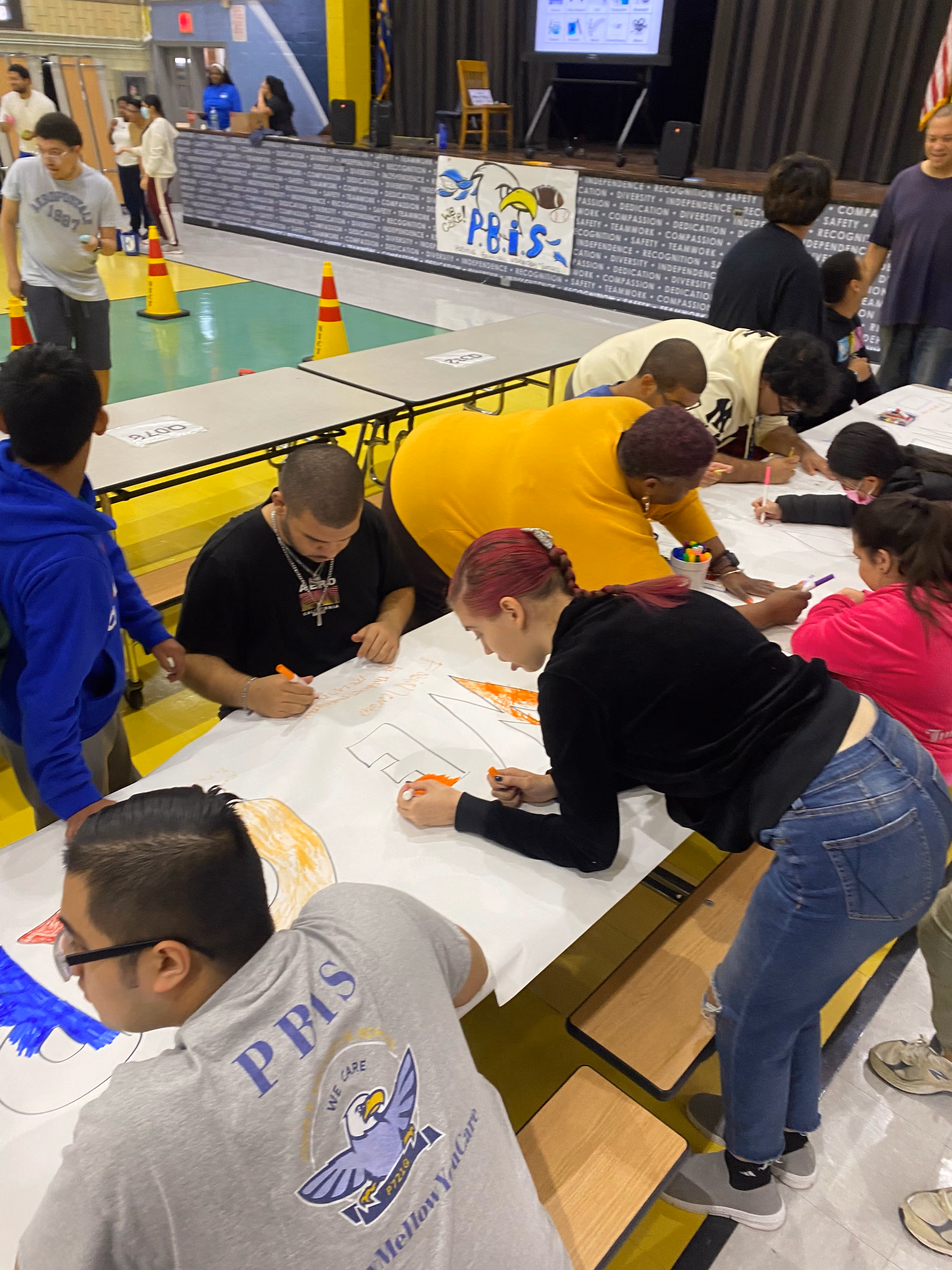 Students collaborating on a large art project during a PBIS school event