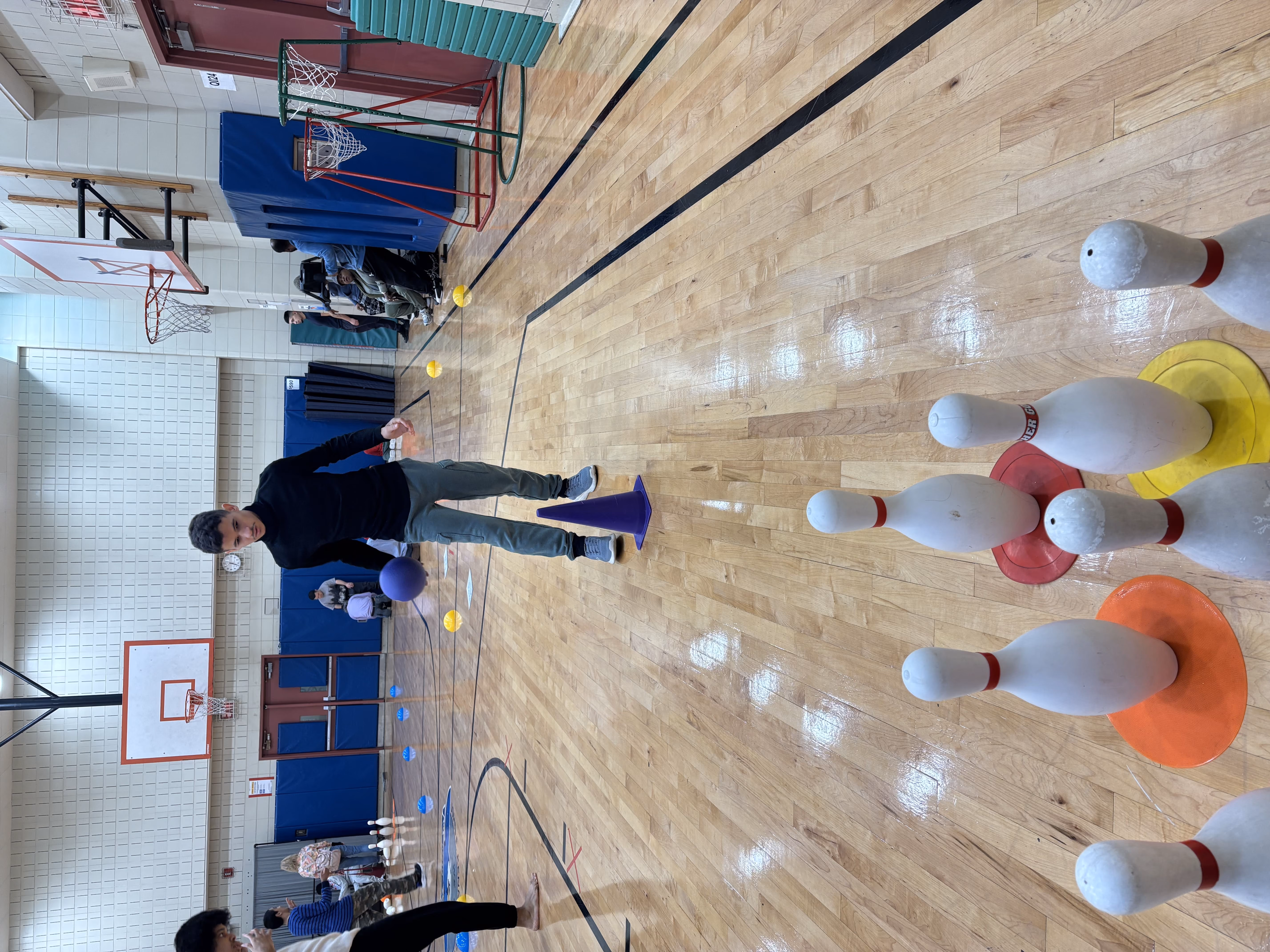 Student bowling with oversized pins in school gymnasium