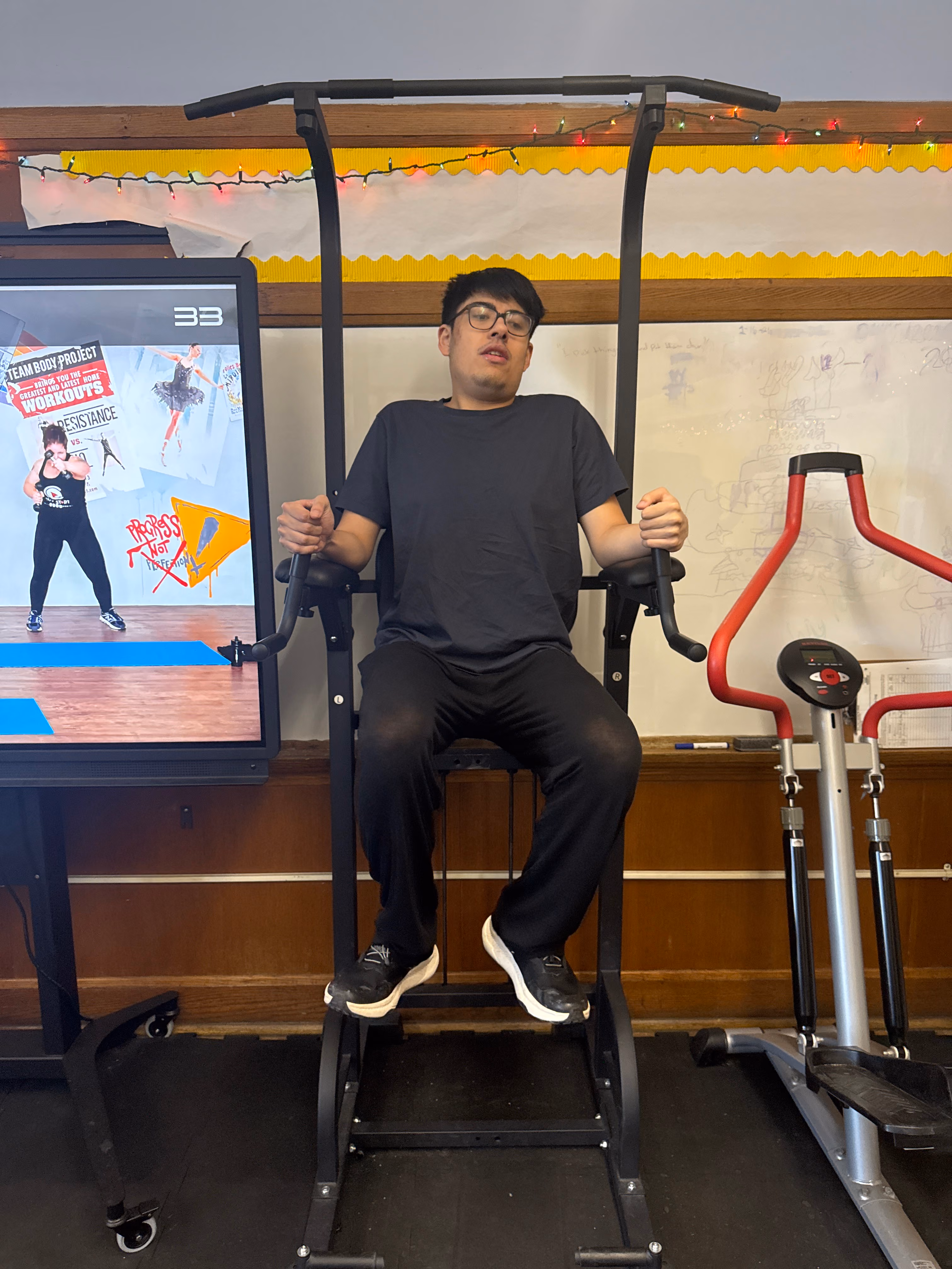 Student using gym exercise machine in school fitness area