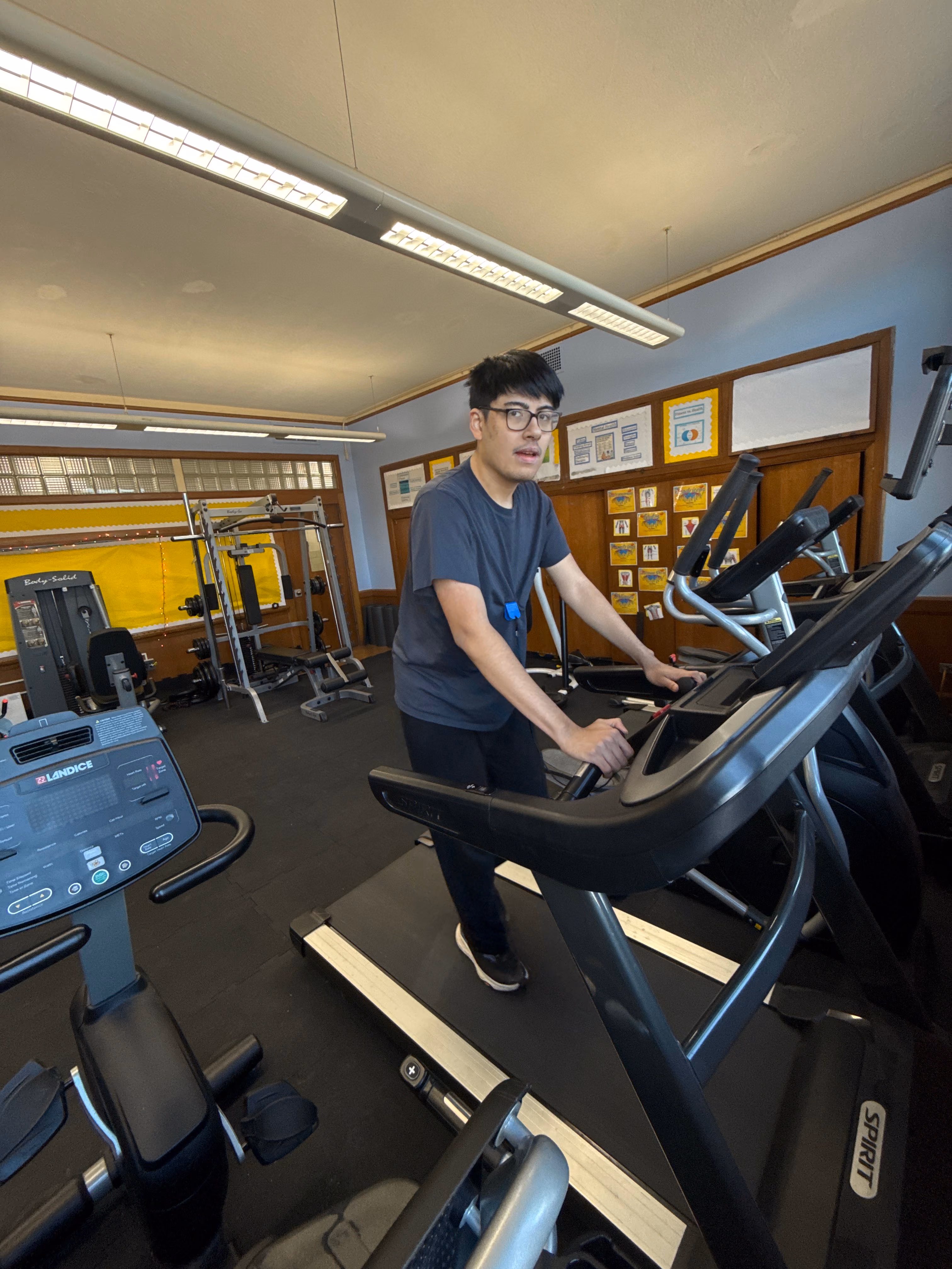 Student using an elliptical machine in the school fitness room