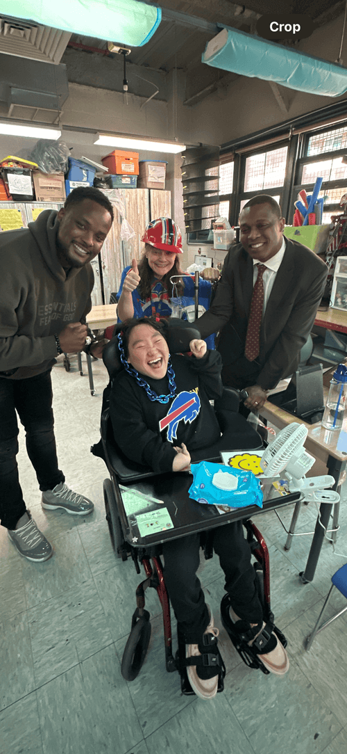 Student in wheelchair smiling with staff during Buffalo Bills spirit day