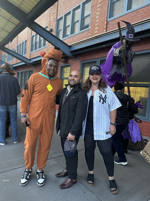 Three staff members posing at a Halloween event in costumes