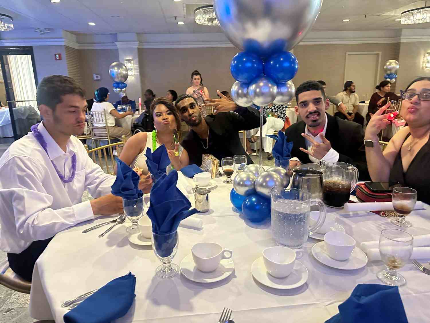 Students posing together at a formal school banquet with blue balloons