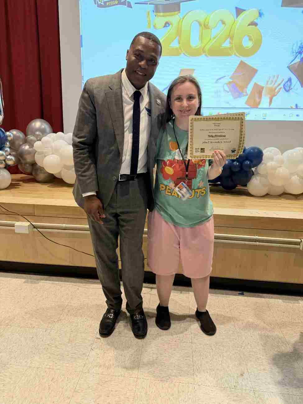 Student holding certificate poses with school principal at ceremony