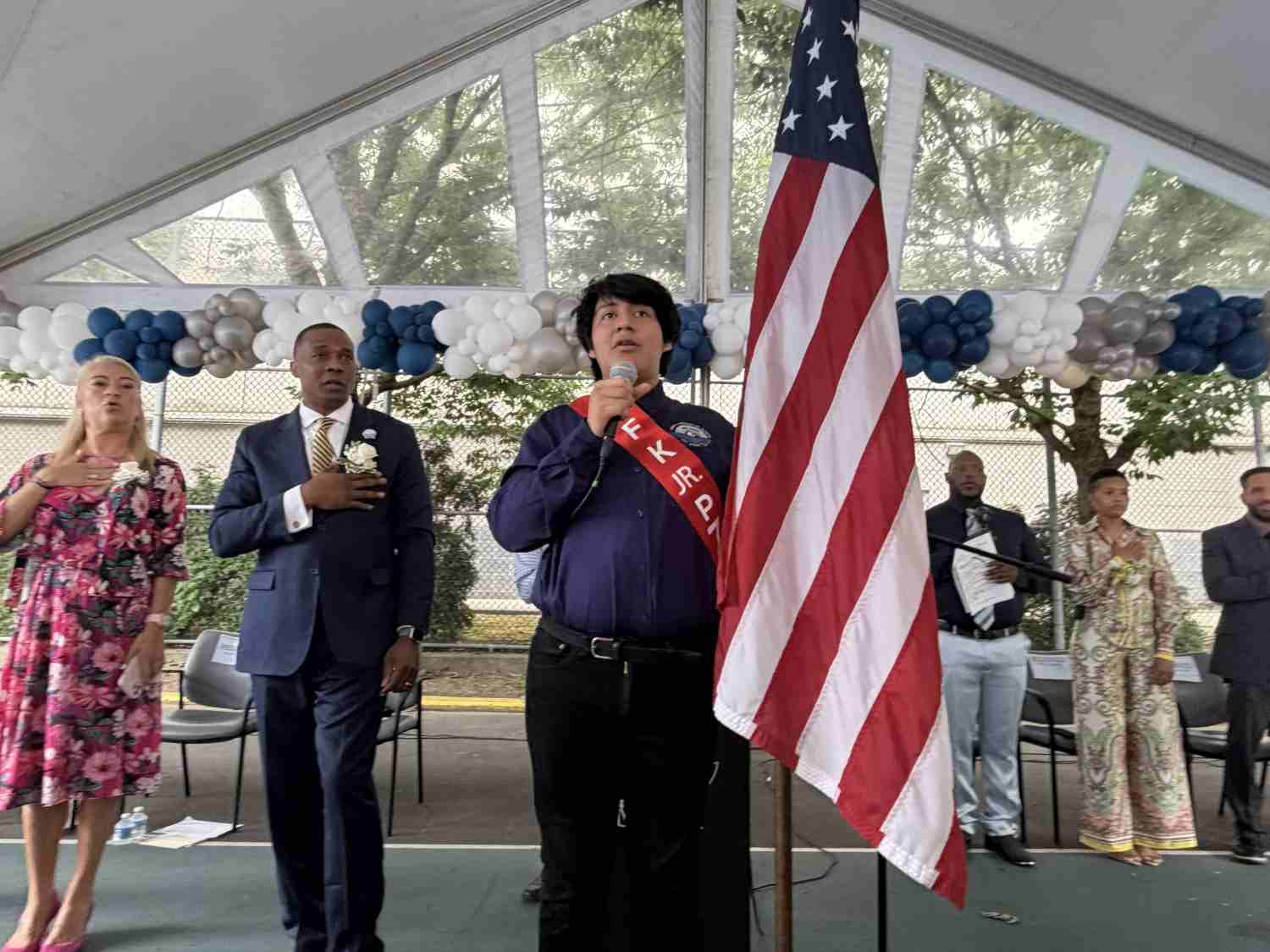 Student leads Pledge of Allegiance at outdoor school ceremony