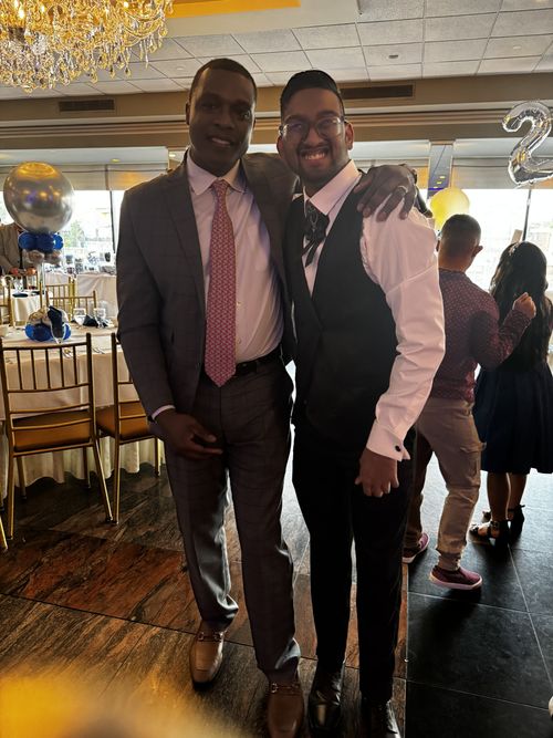 Two formally dressed men posing together at a school celebration event