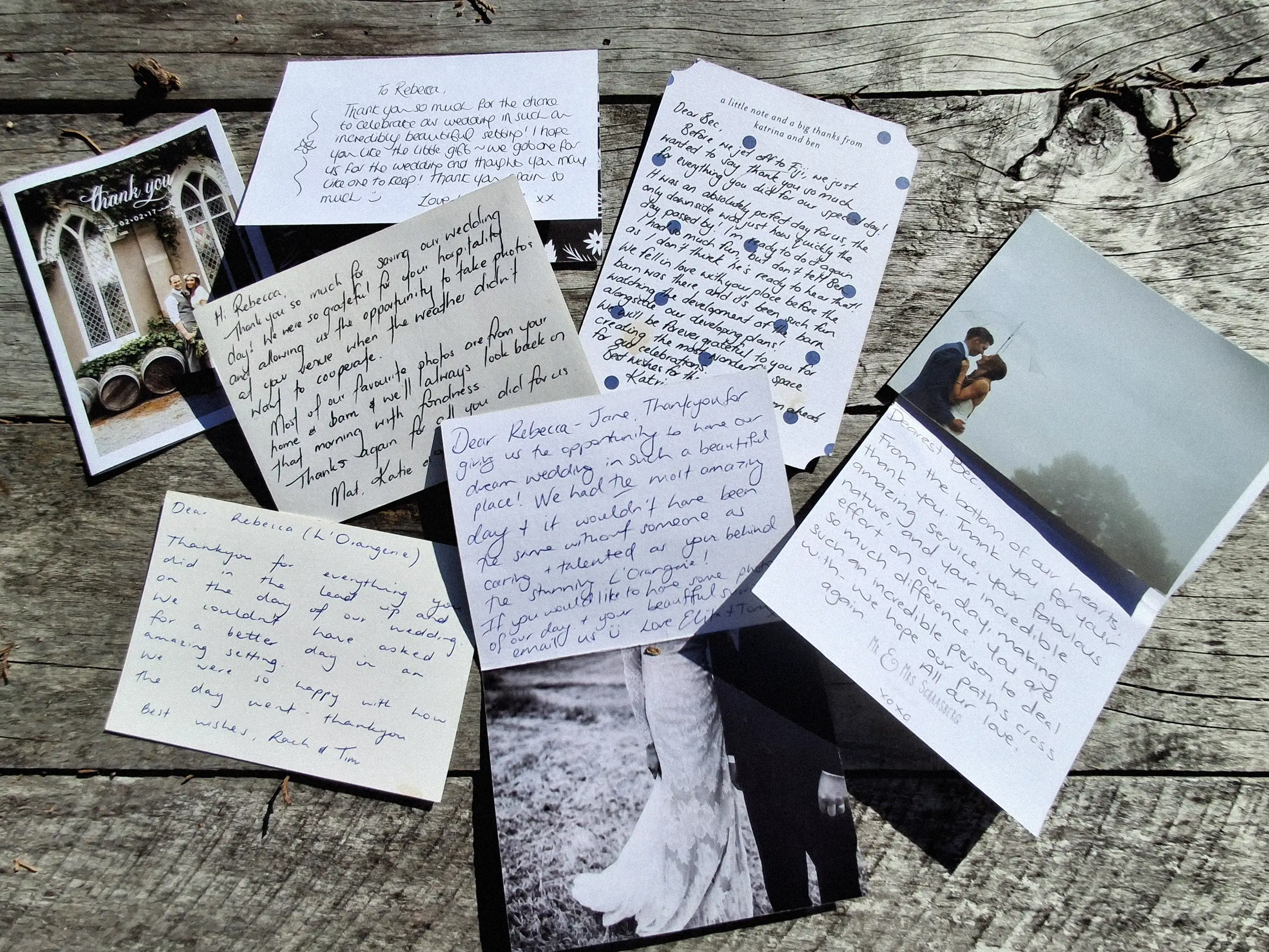 Scattered handwritten letters and cards lie on a wooden surface, along with two small, vintage-style wedding photographs. The notes are written in various styles of cursive and print.