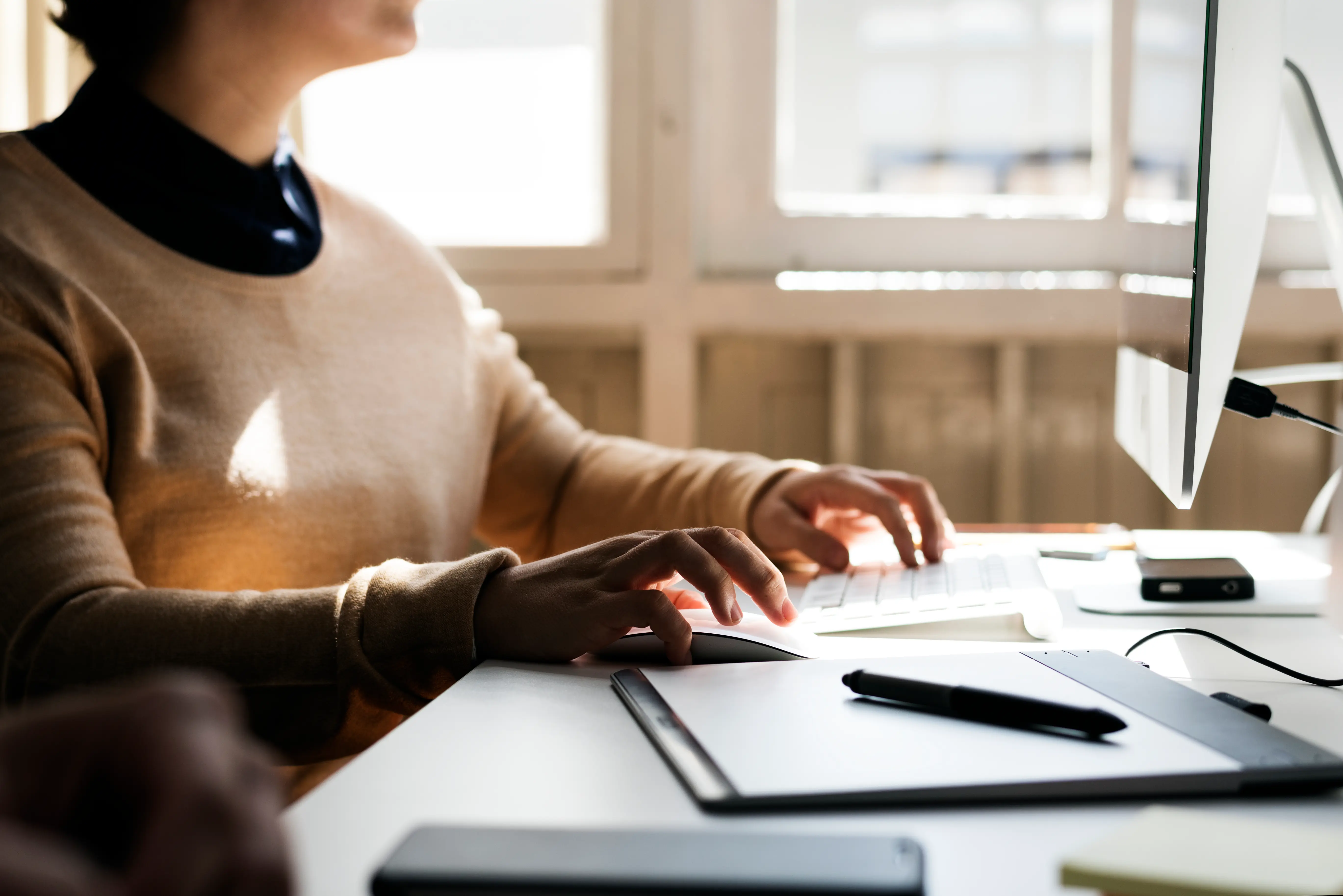 Business woman working on office on computer with notes on her desk 