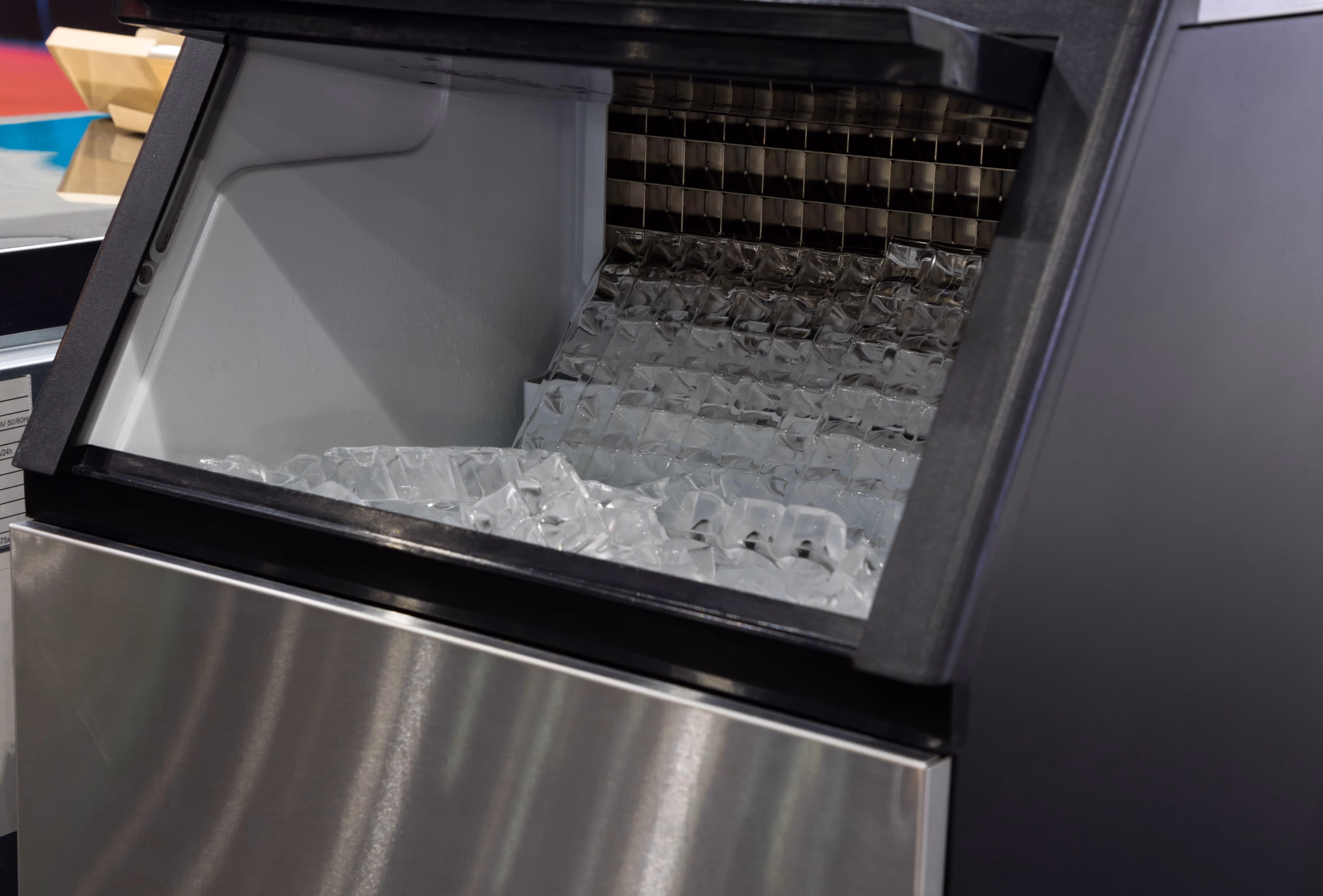 Commercial ice maker machine with clear cube ice visible inside.