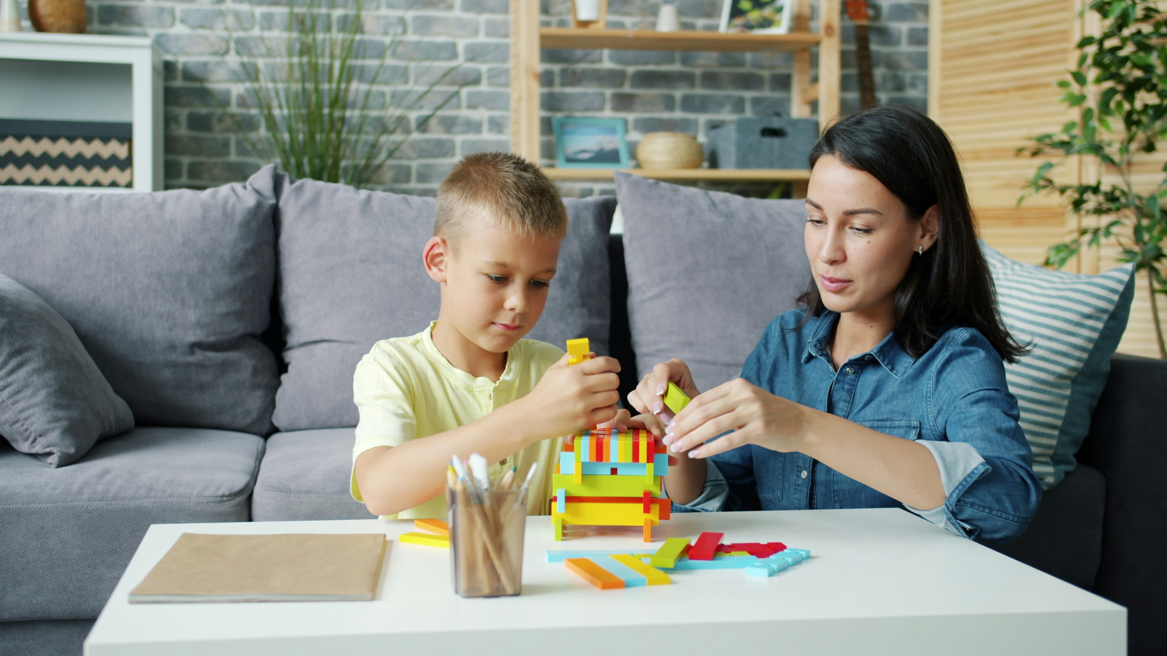 A BCBA therapist smiling with a young child while speaking with the child's parent